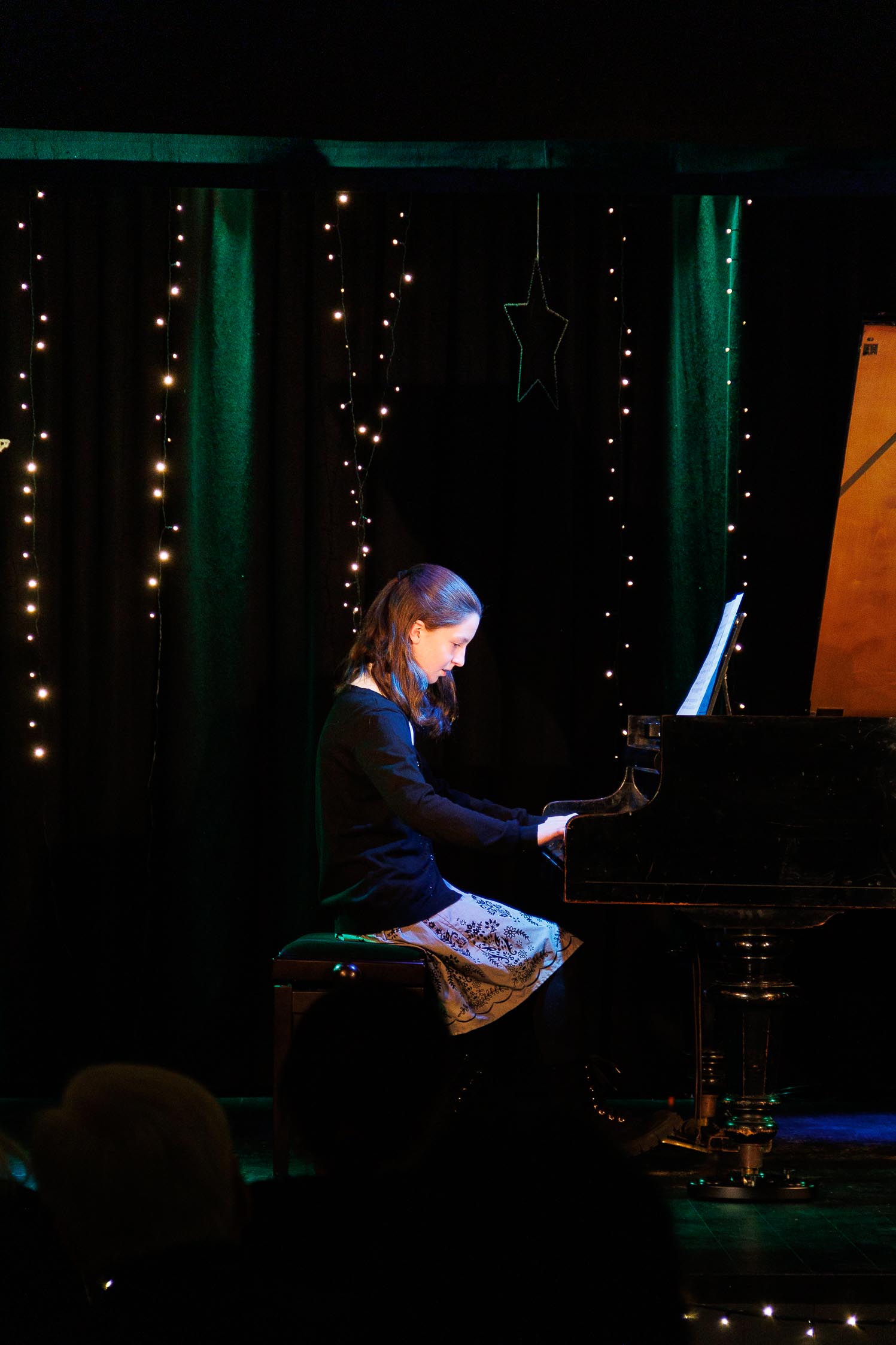 kobieta gra na fortepianie, w tle kolorowa dekoracja świąteczna 