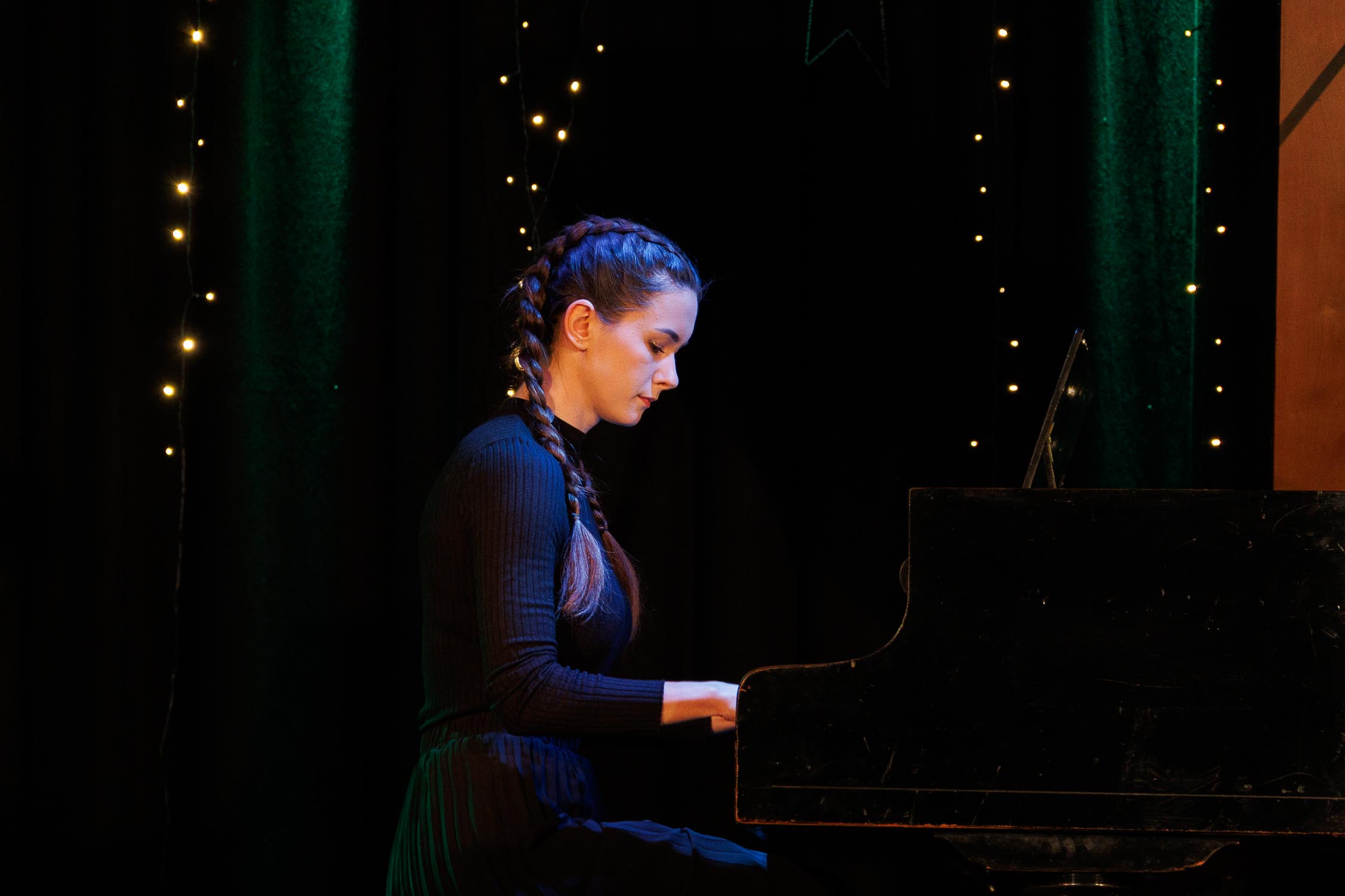 dziewczyna gra na fortepianie, kolorowa scena, widać skupienie na twarzy i jej dłonie na klawiaturze