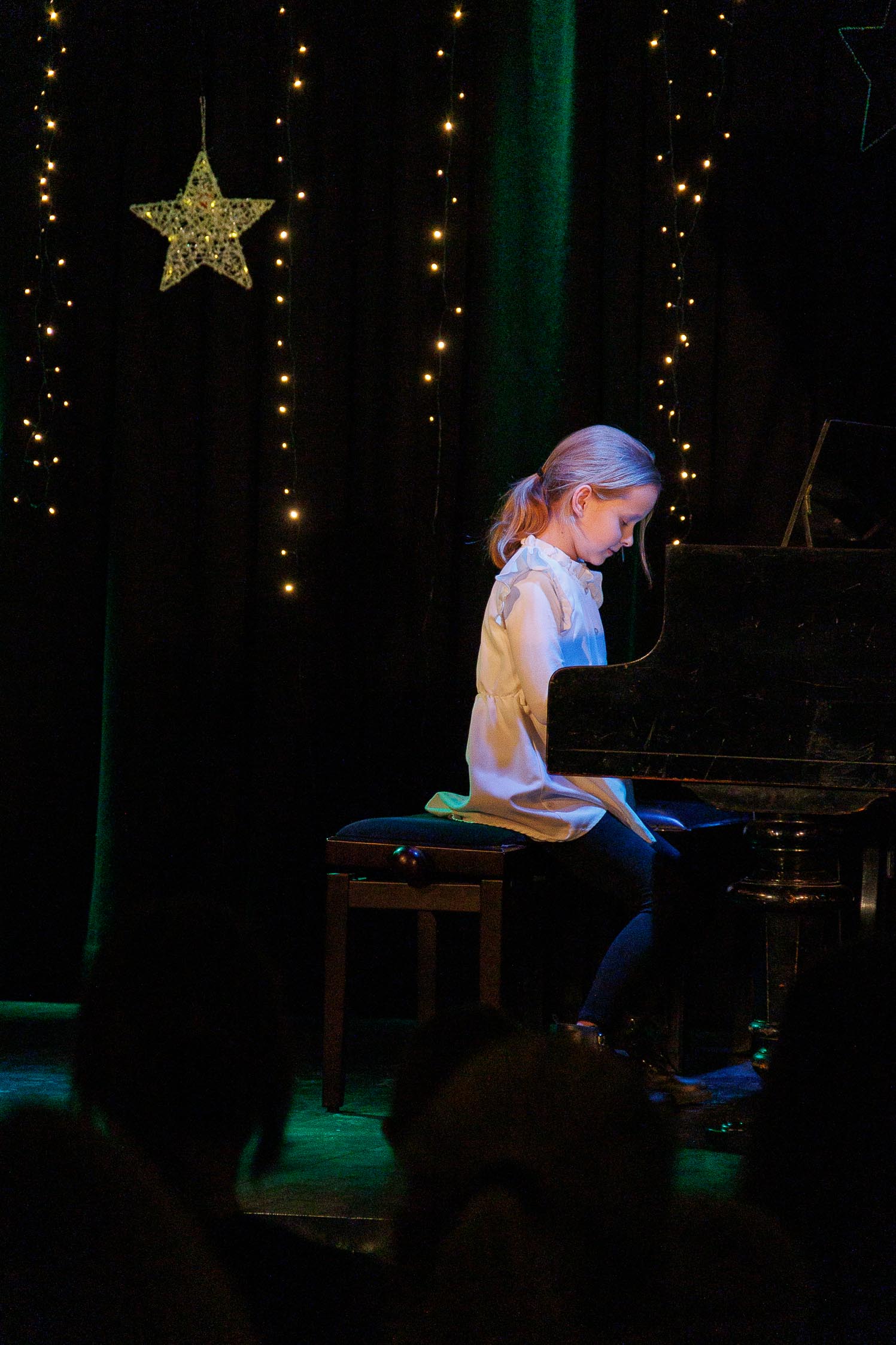 dziewczynka siedzi przed fortepianem i gra , daleki kadr, widać całą scenę
